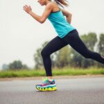 Runner wearing thick-soled maximum cushioning running shoes on asphalt road demonstrating shock absorption technology