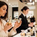 Woman comparing designer perfume bottles at a department store fragrance counter