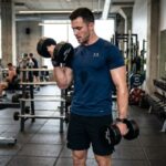 A fit man wearing a moisture-wicking athletic t-shirt while lifting weights in a modern gym