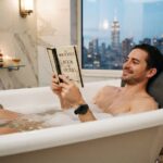 Man relaxing in a bathtub using a NY relaxation pillow.